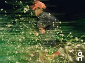 Runner in bright orange cap running past green foliage captured with long exposure motion blur