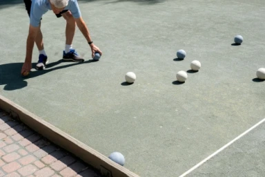 Elderly man in a blue t-shirt playing bocce ball on an outdoor court