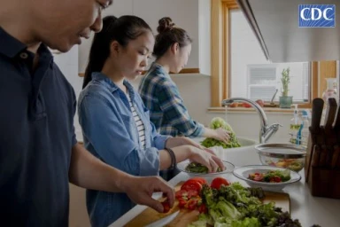 Three people preparing food together in a modern home kitchen with fresh vegetables on the counter.