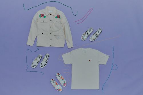 Flat lay of a cream jacket with rose designs, checkered and floral sneakers, and a cream t-shirt arranged on a purple background.