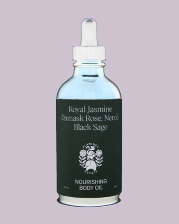 Glass bottle of body oil with white dropper cap against a plain light mauve background