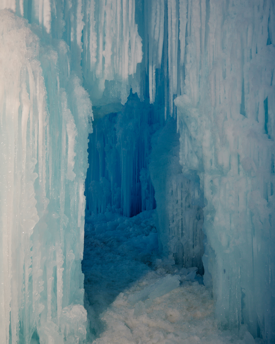 Icy cavern created from frozen ice with blue and white colorations, and a passage formed into the ice structure. 