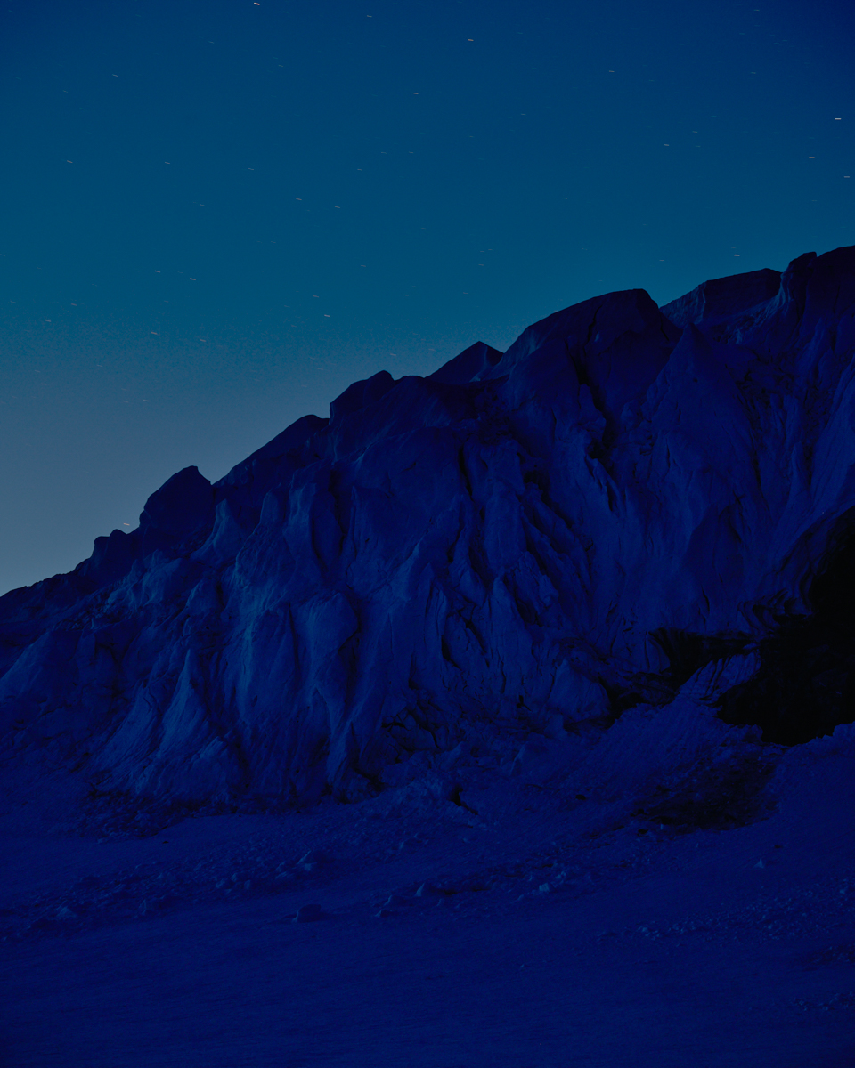 Dramatic night landscape of a rocky mountain range under a starlit sky, showcasing a serene, dark environment and natural beauty.