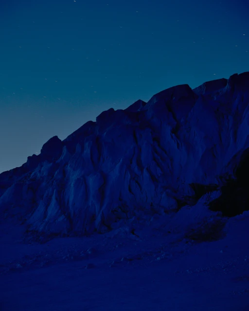 Dramatic night landscape of a rocky mountain range under a starlit sky, showcasing a serene, dark environment and natural beauty.