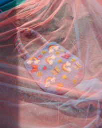 Beaded handbag decorated with rainbows, butterflies, and smiley faces behind pink tulle fabric