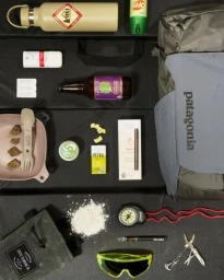 Flat lay photography featuring outdoor gear, a Patagonia backpack, water bottle, and various accessories on dark background.