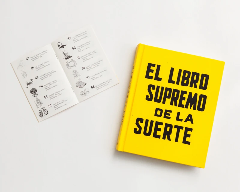 Yellow book titled 'El Libro Supremo de la Suerte' with a spread of a booklet with line drawings and text on a white background.