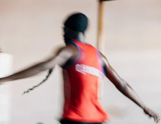 Motion-blurred figure in a red athletic tank top with arms outstretched photographed by Rose Marie Cromwell.