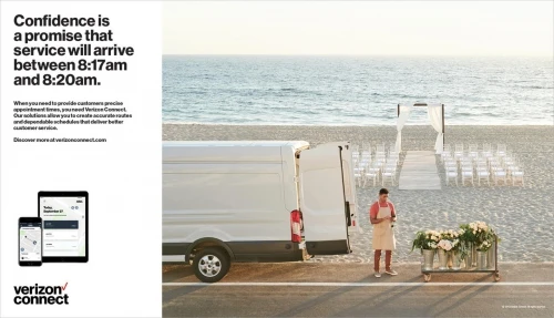A delivery van parked on a road next to a beach with a wedding setup. A worker wearing an apron stands next to a cart of flowers.