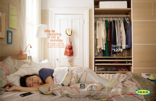 Indoor bedroom scene featuring a woman sleeping in a bed with neutral bedding, adjacent to a wardrobe, illuminated by soft, natural light.