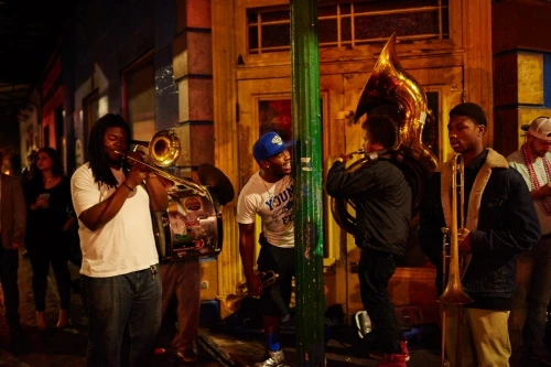 Nighttime street scene of a group of African-American musicians playing brass instruments, with passersby in the background.