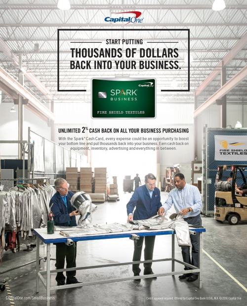 Capital One ad in a textile factory with three workers inspecting materials at a table, promoting business cash back rewards.