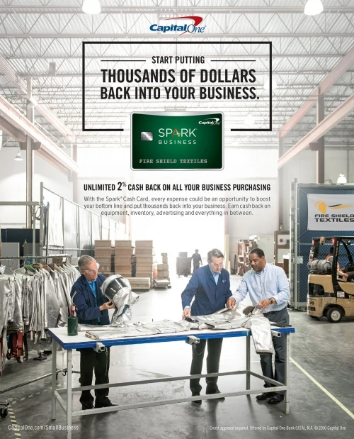 Capital One ad in a textile factory with three workers inspecting materials at a table, promoting business cash back rewards.