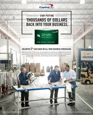 Capital One ad in a textile factory with three workers inspecting materials at a table, promoting business cash back rewards.