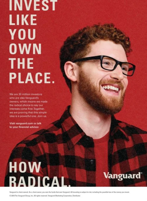 Smiling man with glasses in a flannel shirt against a red background, financial advertisement for Vanguard with the text 'Invest Like You Own The Place'.