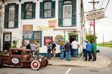 People gathered outside Elizabeth's restaurant with a rusty vintage rat rod truck parked on the street