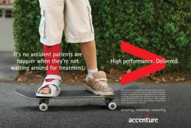 Close-up of a child on a skateboard, one leg in a red cast and orthopedic sandal, beside a green hedge.