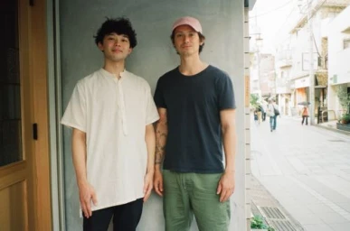 Two men standing together outdoors on a street, wearing casual clothing, photographed by Balazs Gardi.
