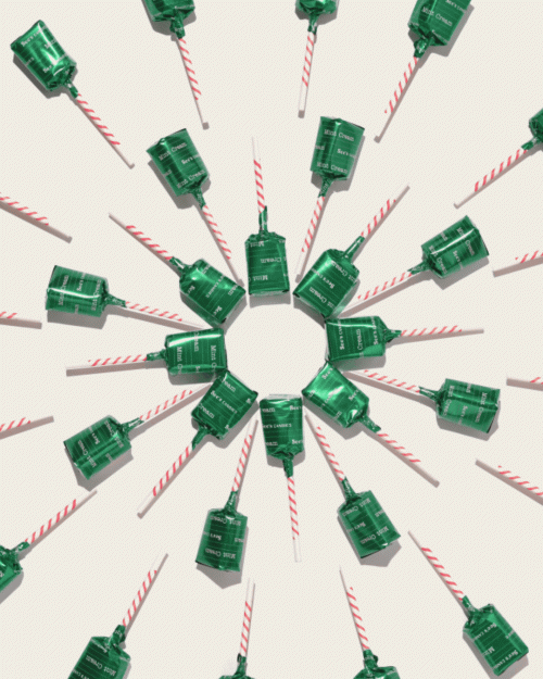 Overhead shot of multiple green and white party poppers arranged in a radial pattern on a white surface. Party favors and decorations.