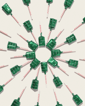 Overhead shot of multiple green and white party poppers arranged in a radial pattern on a white surface. Party favors and decorations.