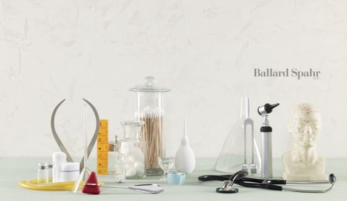 Medical still life featuring stethoscope, tuning fork, vials, mannequin head, and other healthcare items against a neutral backdrop.