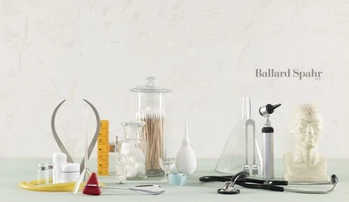 Medical still life featuring stethoscope, tuning fork, vials, mannequin head, and other healthcare items against a neutral backdrop.