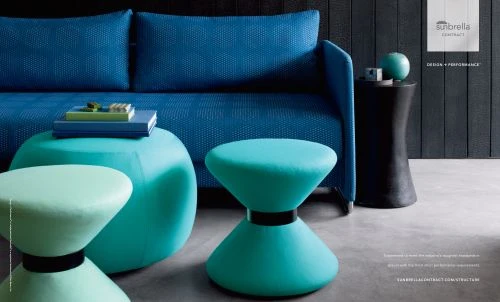 Interior scene featuring a modern blue sofa, teal ottomans, and a sleek black side table against a dark, panelled wall.