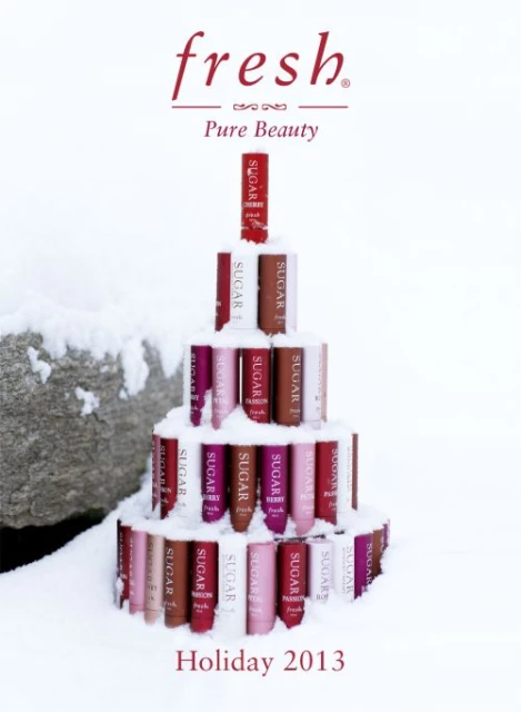 Beauty product tubes are arranged in a Christmas tree shape on snow, promoting Fresh Pure Beauty Holiday 2013 products in a festive scene.