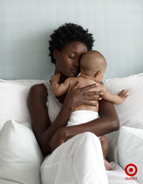 A tender portrait of an African-American woman cradling a baby in a bed, showcasing intimate mother-child bonding with soft lighting.