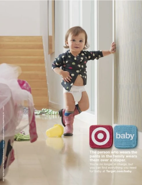 Baby girl in diaper and boots poses indoors against wall in a bright, clean domestic setting, showcasing clothing and Target brand.