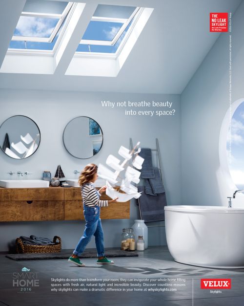 A child in a bright, modern bathroom is holding a construction of white paper; skylights provide natural light. Velux ad.