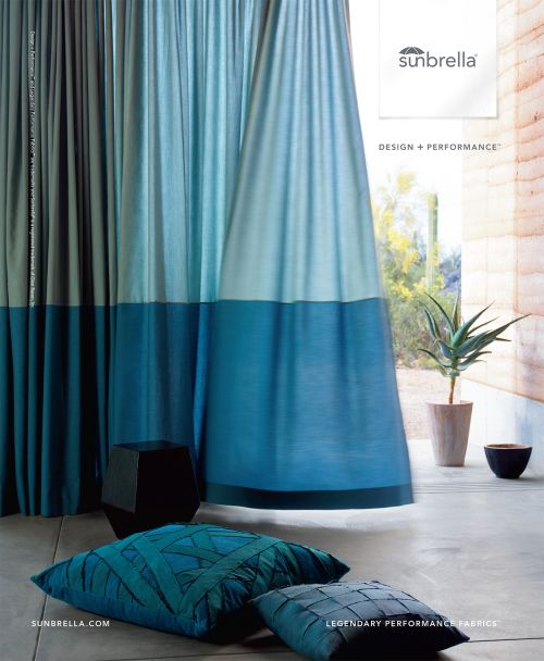 Two-tone blue curtains with pillows and decor in a sunlit interior space; showcases modern interior design with geometric accents.