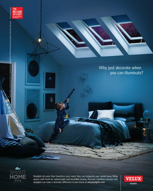 Bedroom interior with skylights showcasing a night sky view. A child in pajamas looks through a telescope. Ad for Velux skylights.