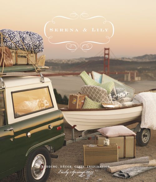 Vintage green and white car towing a boat trailer full of bedding, pillows and luggage near the Golden Gate Bridge at sunset.