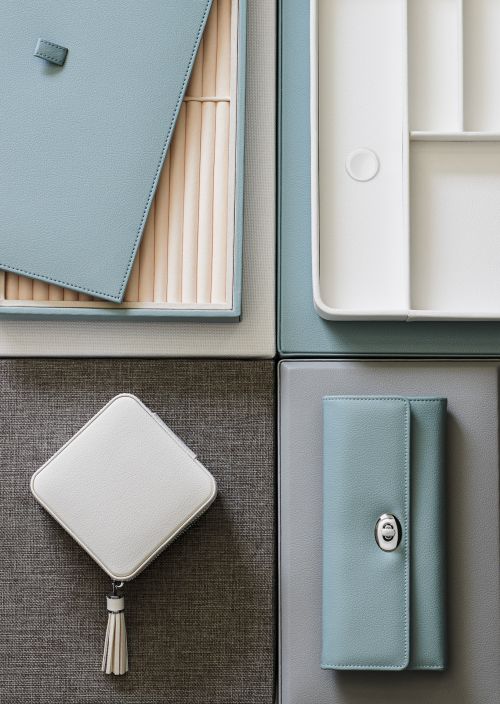 Overhead shot of jewelry boxes and a clutch arranged on textured grey background. Boxes are white and light blue.
