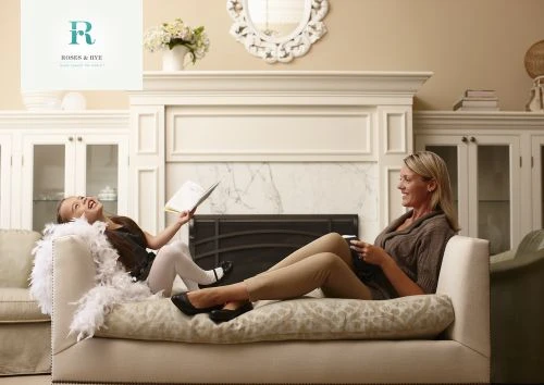 Woman and young girl laughing on a couch in a living room with a fireplace, photographed by Laurie Frankel.