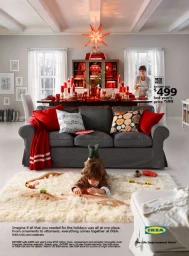 A boy lies on a white fluffy rug playing with a wooden toy train, with a gray sofa and Christmas decorations in the background.
