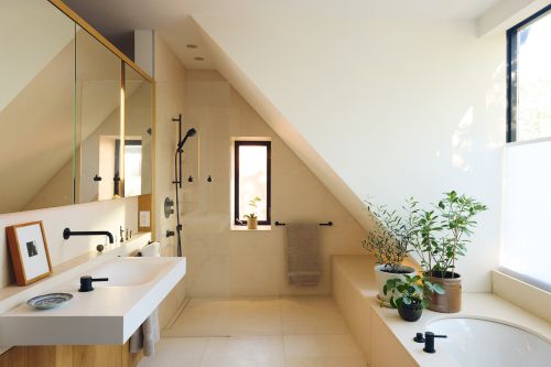Modern bathroom interior features a white countertop sink, bathtub, plants, and a window providing natural light in a home setting.