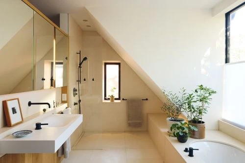 Modern bathroom interior features a white countertop sink, bathtub, plants, and a window providing natural light in a home setting.