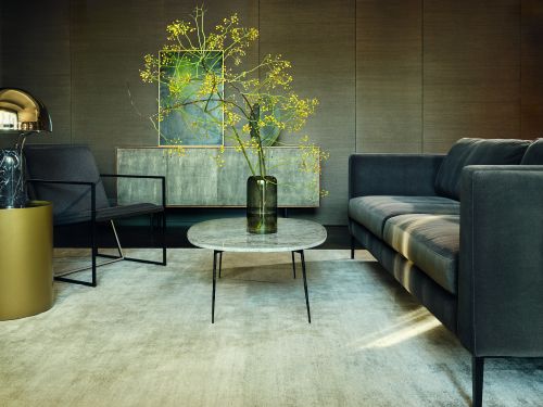 Living room interior featuring a gray sofa, marble coffee table with flowers, chair, and modern console in a home setting.