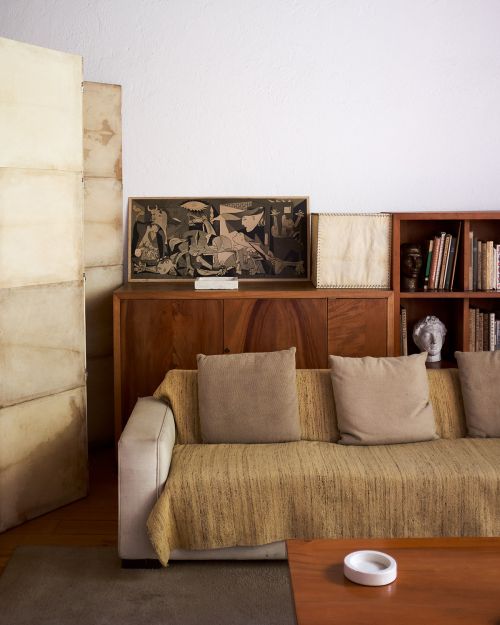 Interior shot of a living room featuring a couch with pillows, a wooden cabinet, artwork, and books creating a cozy, inviting atmosphere.