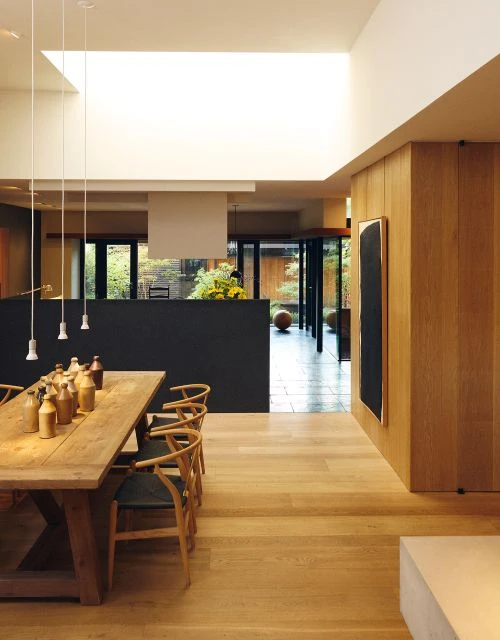 Interior of a home with a wooden dining table and chairs, pendant lights, and an open doorway to an outdoor patio.