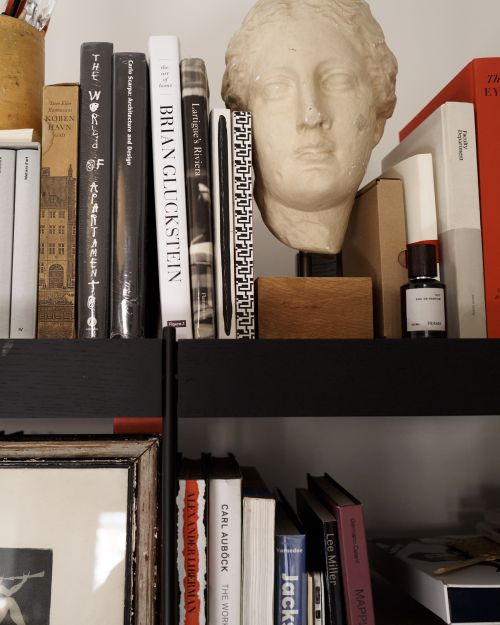 Bookshelf with architectural books, a bust sculpture, and decorative objects in a residential setting creating an editorial style shot.