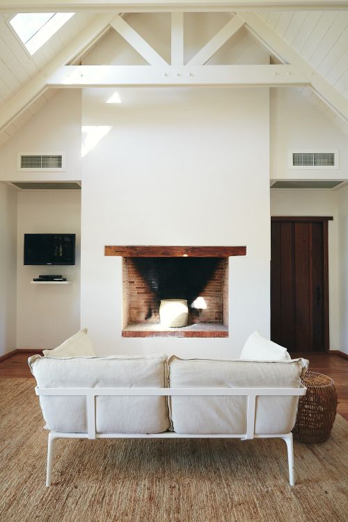 Bright living room interior features a white sofa in front of a brick fireplace, with natural light streaming in from skylights.