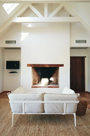Bright living room interior features a white sofa in front of a brick fireplace, with natural light streaming in from skylights.