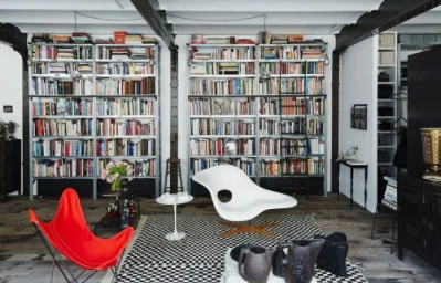 Modern living room interior featuring two tall metal bookshelves filled with books, a white organic lounge chair, and a red butterfly chair.