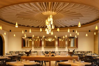 Interior view of a modern restaurant featuring a circular wooden ceiling installation with cascading pendant lighting.
