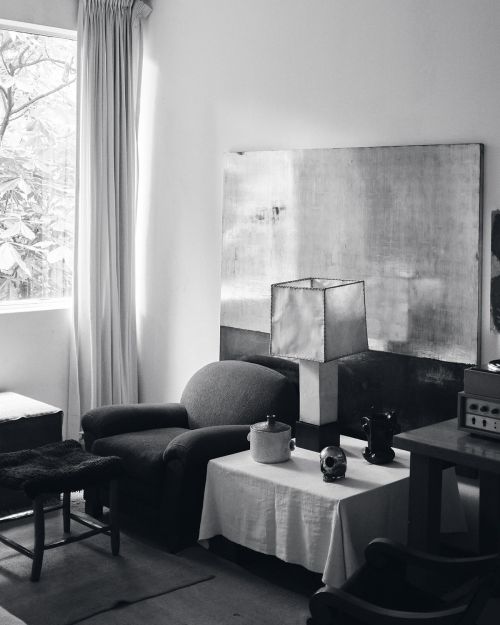 Monochrome interior photograph showing a living room with a table lamp and large abstract artwork by Graydon Herriott