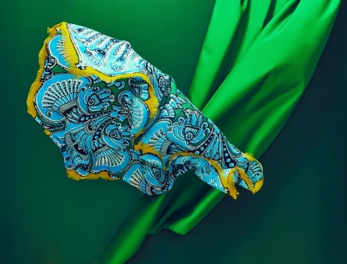 Silk scarf with ornate floral pattern on a green background, evoking elegance and luxury.