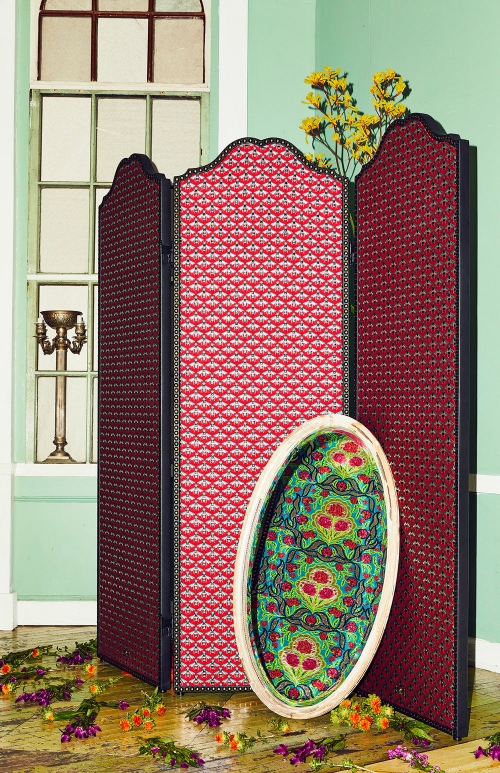 Interior photograph of a folding screen and decorative table with floral arrangement, and natural light from window in background.